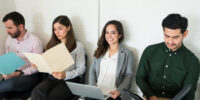 Confident candidate using laptop while sitting with competitors at job interview in office