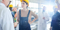 Waist up portrait of female factory worker slapping mature managers across face during protest in industrial workshop, copy space
