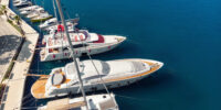 Scenic aerial  view many yachts boats moored at Croatian bay harbor shore blue turquoise clear water at bright summer sunny day. Top above Mediterranean sea marina. Boat vessel charter service.
